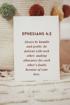 a card with the words ephesians 4 2 and two pom poms