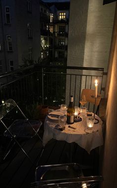 the table is set on the balcony at night with two candles in front of it