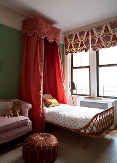 a bedroom with a bed, chair and ottoman in it's corner next to a window