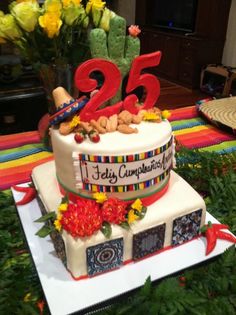 a decorated cake with the number twenty five on top and flowers in front of it