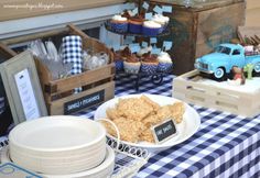 a table topped with plates and cups filled with desserts next to boxes of cupcakes