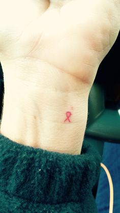 a small pink ribbon tattoo on the wrist