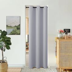 a living room with a white wall and grey curtains on the window sill next to a potted plant