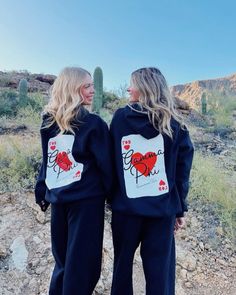 two women wearing matching sweatshirts with hearts and the words love on them in front of a cactus