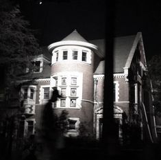 a black and white photo of a person walking in front of a large brick building