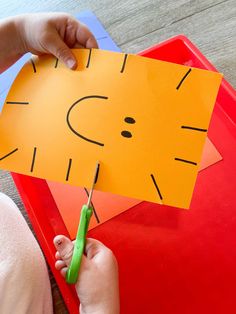 a child is cutting paper with scissors on a red tray that has a cat face