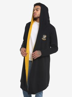 Meet in the middle of "Hogwarts uniform" and "casual hoodie" with this Harry Potter hooded cloak! Inspired by Hufflepuff house  this cloak features the Hufflepuff crest embroidered at the chest  interior lining in house colors  a pointed hood and draped hemline. Plus  when you're not casting spells  keep your wand close by in the hidden  interior wand pocket!52% cotton; 58% polyesterWash cold; dry lowInterior wand pocketImportedListed in men'sunisex sizesModel wears size Medium Hot Topic Harry Potter, Hufflepuff Crest, Hogwarts Uniform, Casting Spells, Hufflepuff House, Harry Potter Hufflepuff, Culture Clothing, Her Universe, Hooded Cloak