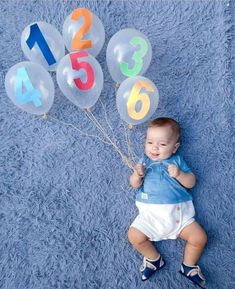 a baby is laying on the floor with balloons in front of him that say numbers