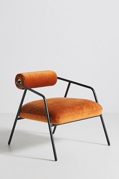 an orange chair sitting on top of a white floor next to a black metal frame