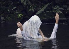 a woman is floating in the water with her hands up