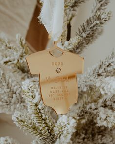 a gold ornament hanging from a tree with white flowers in the foreground