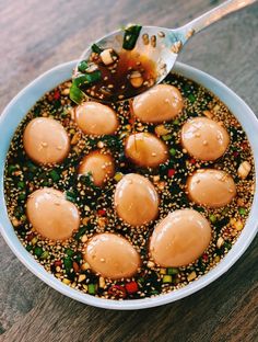 a bowl filled with food on top of a wooden table next to a metal spoon