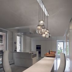 a modern kitchen with white counter tops and lights hanging from the ceiling