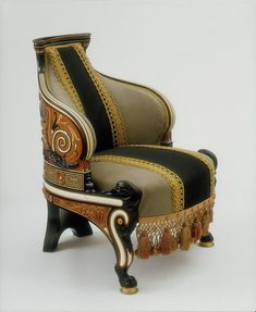 an ornate chair with tassels on the legs and foot rests against a white background