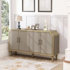 a sideboard with two framed pictures on the wall