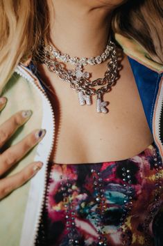 a close up of a woman wearing a necklace and jacket with multiple charms on it