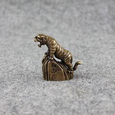 a small bronze tiger figurine sitting on top of a rock