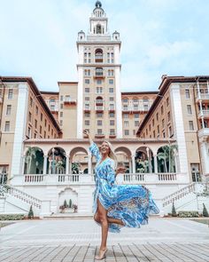 a woman is dancing in front of a large building