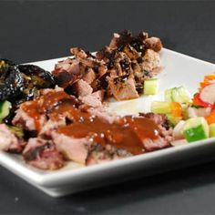 a white plate topped with meat and veggies on top of a black table