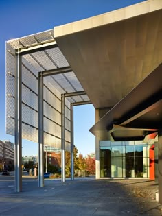 an empty parking lot next to a large building with glass doors and metal poles on both sides