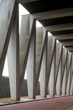 a long row of concrete pillars on the side of a building with red carpeting