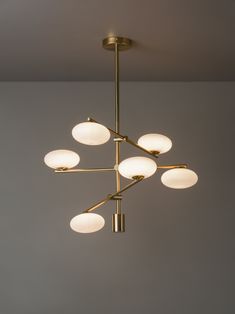 a chandelier with six lights hanging from it's center and four circular shades on the ceiling