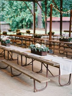 tables with white tablecloths and flowers on them under a tented outdoor venue