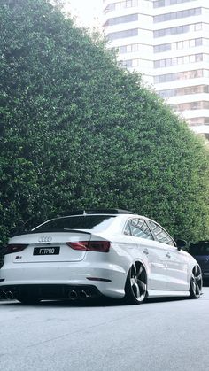 a white car is parked in front of some trees