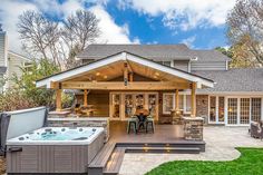 a hot tub sitting on top of a wooden deck next to a patio with chairs