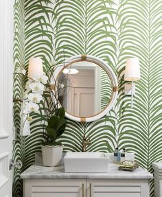 a bathroom with green palm leaves on the wall and a white sink in front of it