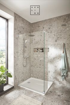 a bathroom with a walk in shower next to a window and a rug on the floor