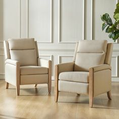 two chairs sitting next to each other on a hard wood floor in front of a white wall