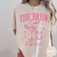 a woman wearing a t - shirt that reads the bride and has a drink in it