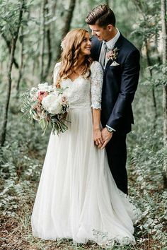 a bride and groom standing in the woods