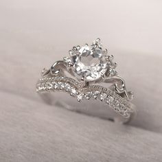 a white gold ring with an oval cut diamond surrounded by smaller round diamonds on the band