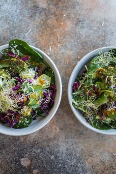 two white bowls filled with salad on top of a cement floor next to each other