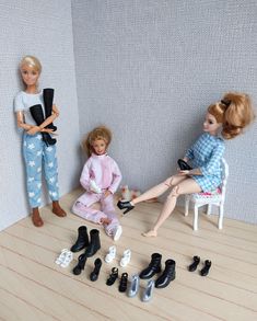 two dolls are sitting on the floor in front of several pairs of shoes