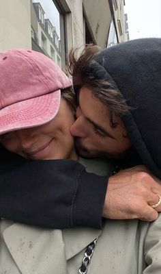 two people hugging each other in front of a building