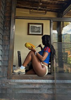 a woman sitting on top of a window sill with a banana in her hand