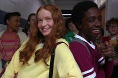 a group of young people standing next to each other in a hallway with one girl smiling at the camera