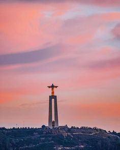 an airplane flying over the top of a tall tower with a cross on it's side