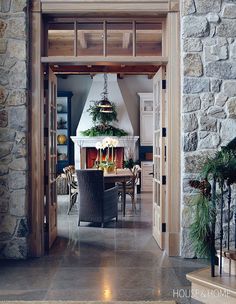 an open door leading to a kitchen and dining room area with stone walls, wood trimming