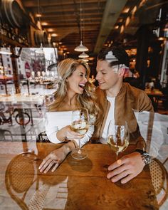 a man and woman sitting at a table with wine glasses