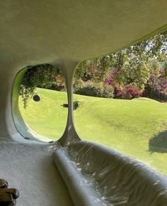 the inside of a house with an oval window looking out onto a green field and trees