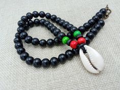 The necklace is 20 inches long. The necklace closes with a clasp. The necklace is beaded with wooden red, black and green beads. The cowrie shell pendant is approximately 1 inches long and 0.50 inches wide. If you have any questions please feel free to contact us at anytime. Black 8mm Beads Beach Jewelry, Black Beaded Jewelry For Beach, 8mm Beads, Black Beach Jewelry With 8mm Beads, Black Necklaces With Colorful Beads For Beach, Black Wooden Beads For Beach, Black Necklaces With Large Beads For Beach, Black Wooden Beads Necklace For Beach, Black Spiritual Necklace For Beach, Traditional Black Necklaces For The Beach