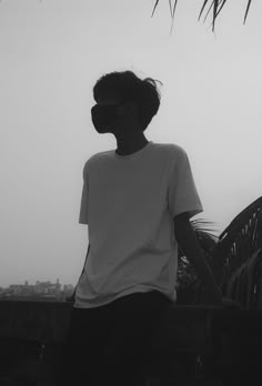 black and white photograph of person wearing blindfold standing on bridge with cityscape in background