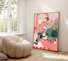 an abstract painting hangs on the wall next to a white chair and round ottoman in front of a window