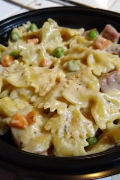 a black bowl filled with pasta and meat on top of a white tile countertop