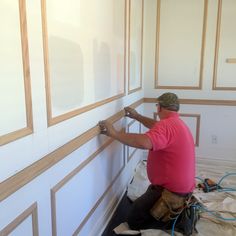 a man is working on the wall in his house with wood trimmings and paint