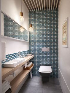 a bathroom with blue and white tiles on the wall, toilet and sink in it